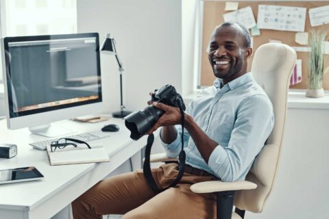 Man Holding Digital Camera And Smiling